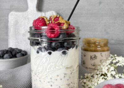 Ein Glas mit fermentierten Overnight Oats, geschichtet mit cremigem Kefir oder Buttermilch, frischen Heidelbeeren und Himbeeren. Getoppt mit einem Klecks Pistazienmus und Hanfsamen – ein sommerliches Frühstück, das sättigt und gut tut.